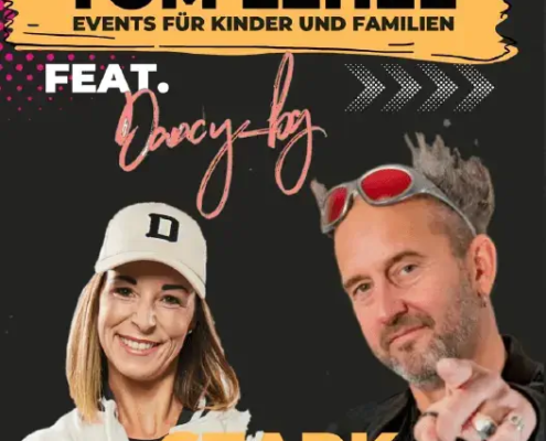 Tom Lehel und Künstlerin Dany performen energiegeladen auf der Bühne des „Starkmacher! – Das Konzert“. Im Hintergrund ist ein farbenfrohes Banner mit den Werten Mut, Respekt und Gemeinschaft zu sehen. Kinder und Eltern im Vordergrund jubeln und klatschen.